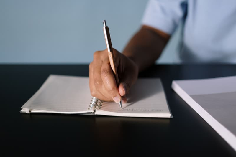 Hand schreibt Notizen in ein Notizbuch