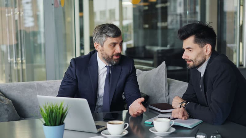 Zwei Berater besprechen Unterlagen am Laptop